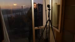 Ylen Moskovan-kirjeenvaihtaja Erkka Mikkonen tekee tv-suoraa hotellihuoneessa. Mikkonen seisoo ikkunalaudalla ja taustalla näkyy hämärä kaupunki..