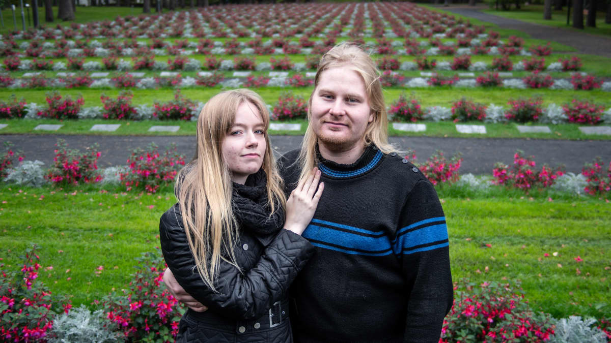 Äärikansallismielinen pariskunta Venla ja Miska Kangasniemi seisovat hautausmaalla ja hymyilevät kameralle.