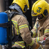 Palomies tarkistaa savusukeltajan varustusta palopaikalla.
