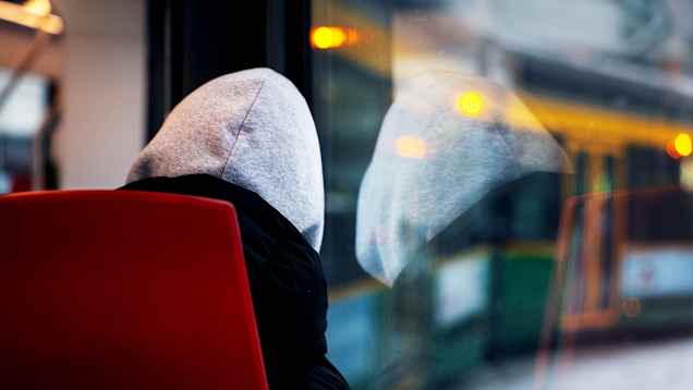 Photo shows a young person sitting on public transport.