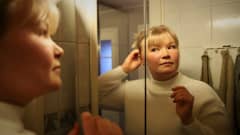 Milja Karvonen katsoo itseään peilistä ja laittaa samalla hiuksiaan kiinni.