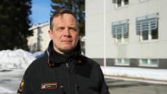 Rajavartiolaitoksen virka-asuun pukeutunut mies katsoo kametaan aurinkoisella talvisäällä.