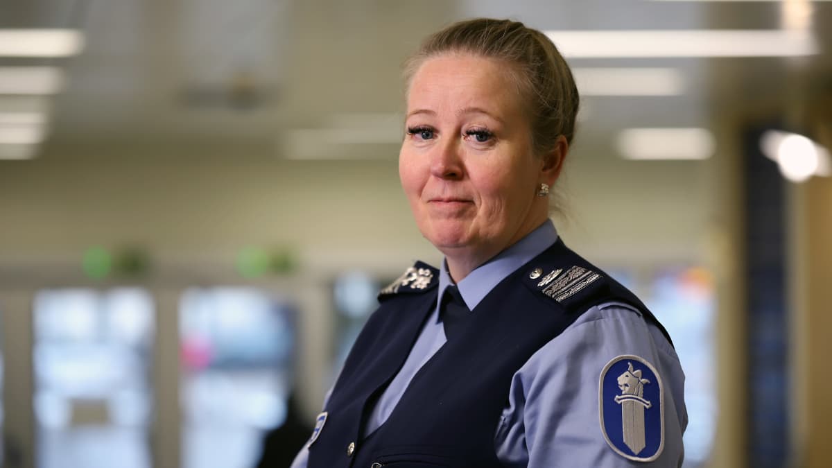 Poliisin virkavaatteisiin pukeutunut, vaalehiuksinen nainen katsoo kameraan.
