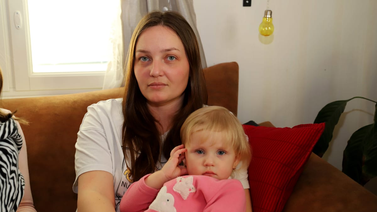 Ukrainasta sotaa pakoon Hausjärvelle saapuneet Iryna Trofimova ja hänen vajaan kahden vuoden ikäinen lapsensa Arina Trofimova istuvat sohvalla. Molemmat katsovat kameraan.