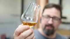 Viskimestari tarkastelee näyteannosta viskilasissa