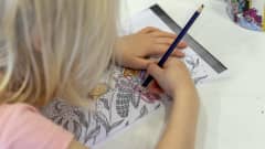 Lapsi värittää päiväkodissa kuvaa puuväreillä