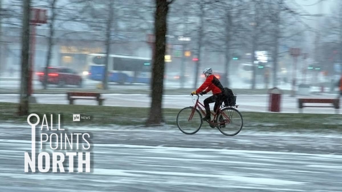 Photo of person cycling in snowy weather on city street, featuring the All Points North podcast logo.