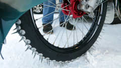 Lumella oleva moottoripyörä rengas, jossa on parin sentin mittaisia, teräviä piikkejä.