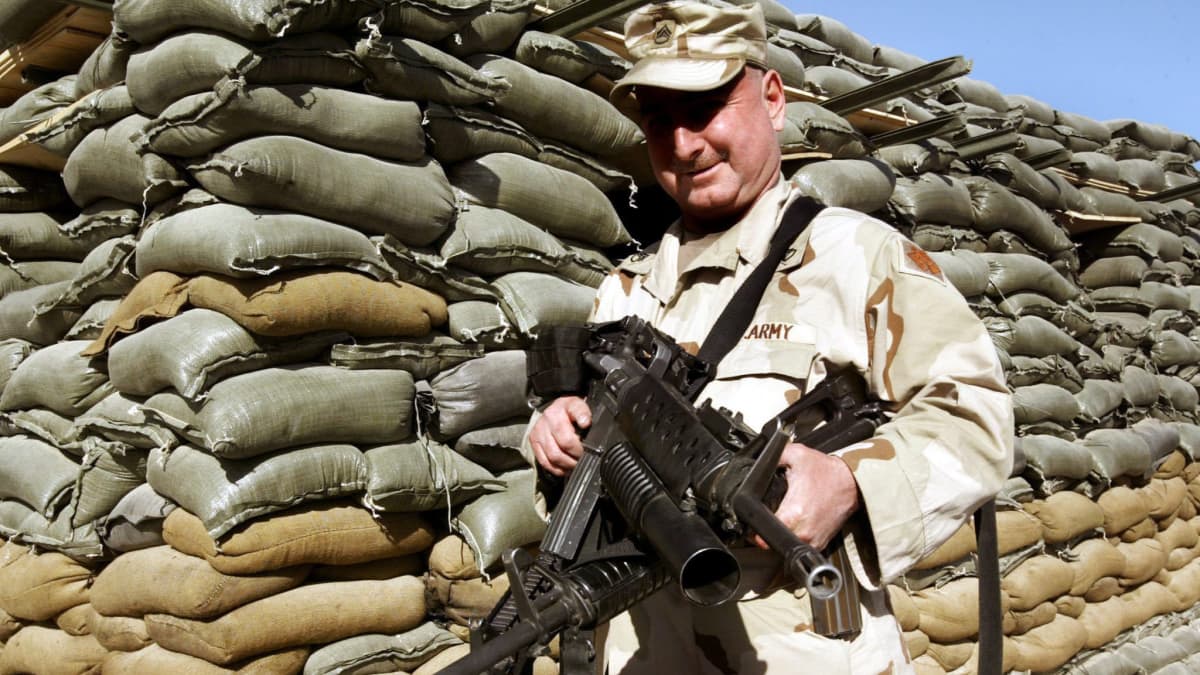 Yhdysvaltain sotilas esittelee kameralle aseita Afganistanissa vuonna 2004. 