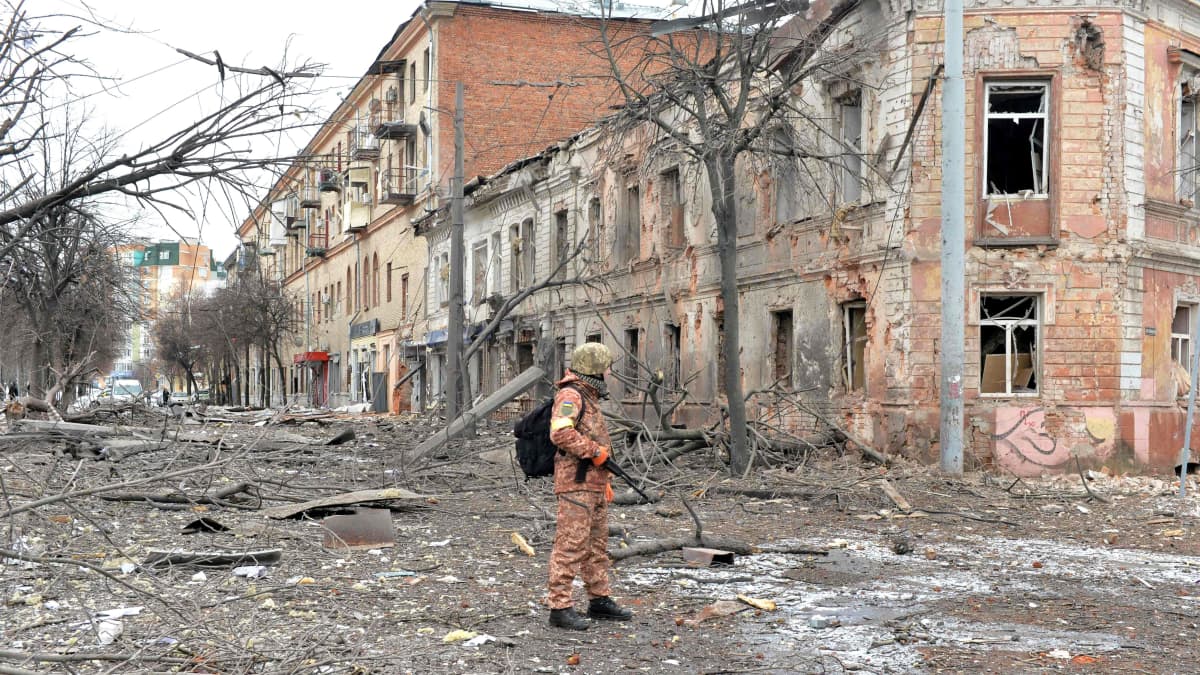Sotilas seisoo tuhoutuneella kadulla.