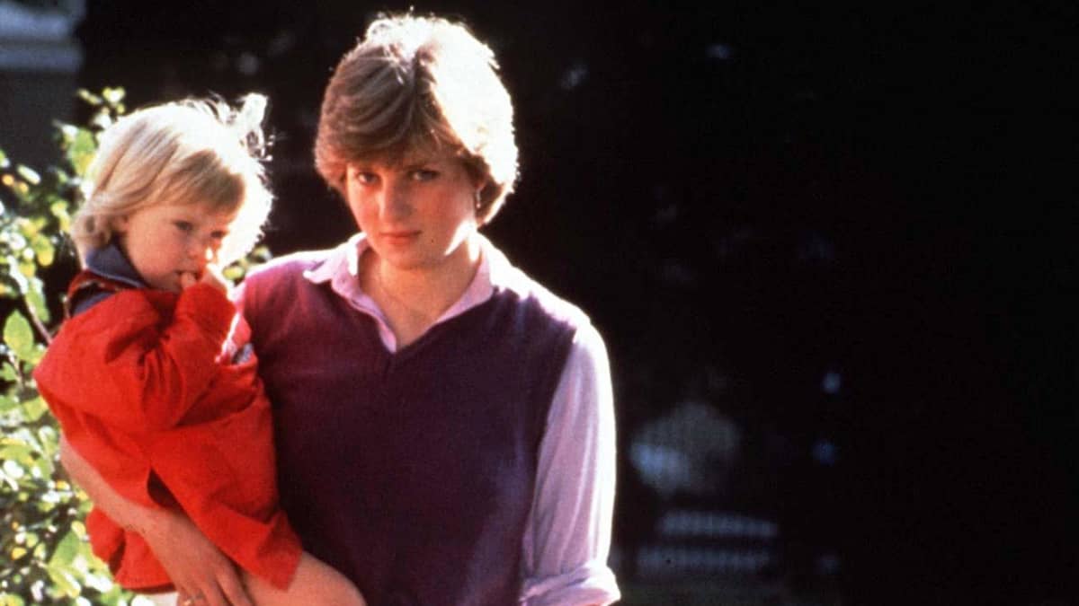 Diana yksi lapsi sylissään ja toinen vierellään. Takaa tuleva valo tekee Dianan hameesta läpinäkyvän.