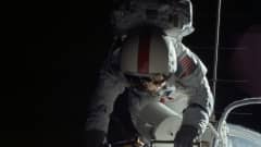 Astronautti avaruusaluksen ulkopuolella pitää kiinni aluksen kyljessä olevista pienistä portaista.