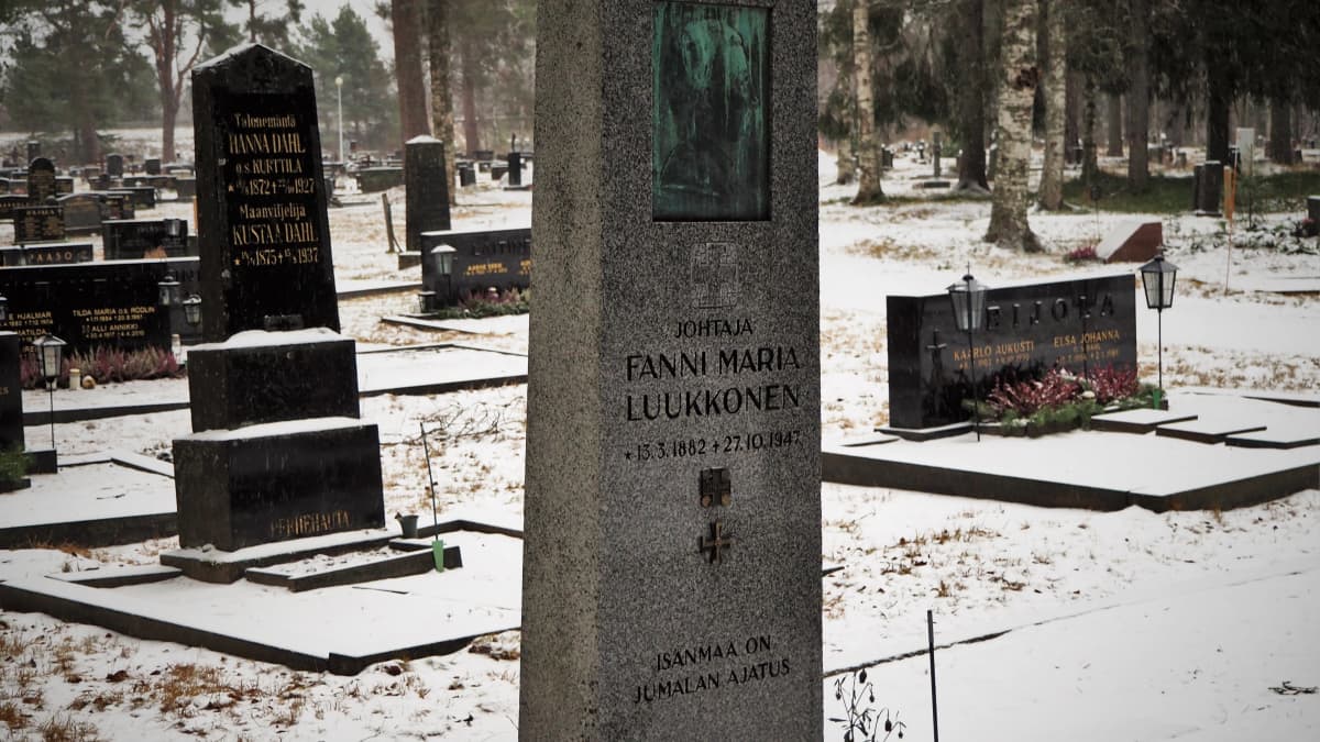 Kivinen hautamuistomerkki, jossa teksti JOHTAJA FANNI MARIA LUUKKONEN. Taustalla luminen Iin hautausmaa.