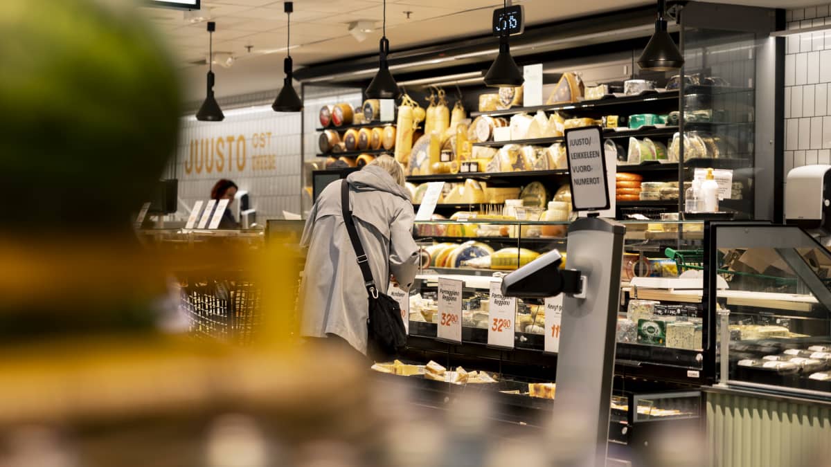 Henkilö kumartuu katsomaan juustoja kylmäaltaasta Stockmannin Herkku-ruokakaupassa.