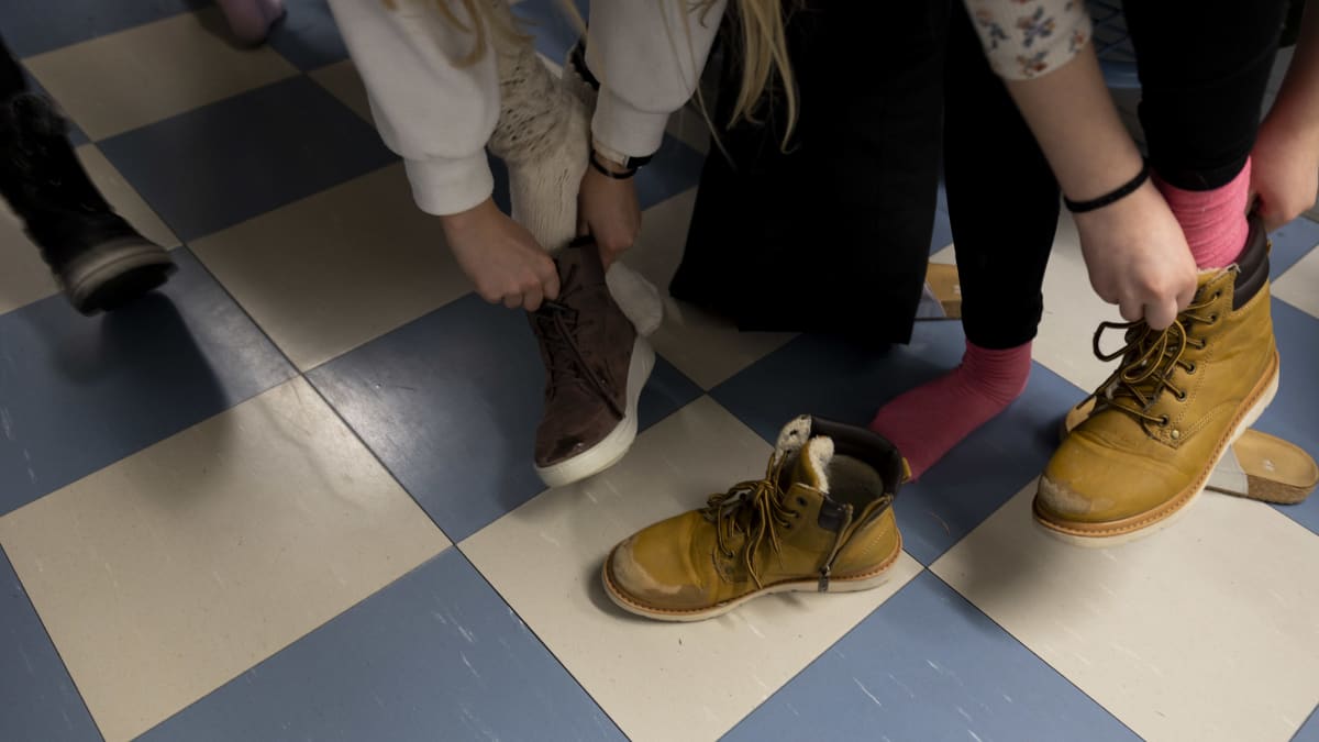 Anonyymi kuva koululaisista laittamassa kenkiä jalkaansa. 