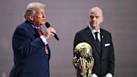 Donald Trump puhuu mikkiin Gianni Infantino vieressään. Edessä on kultainen pokaali, jossa kädet tavoittelevat palloa.