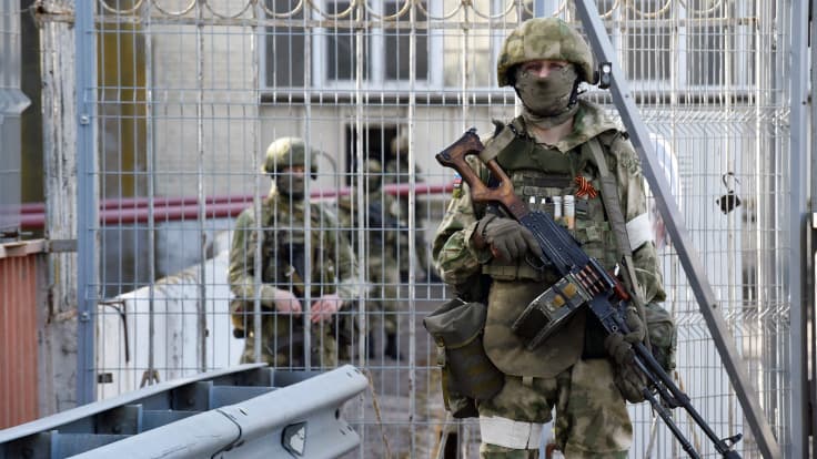 Aseistettu sotilas seisoo portin edessä.
