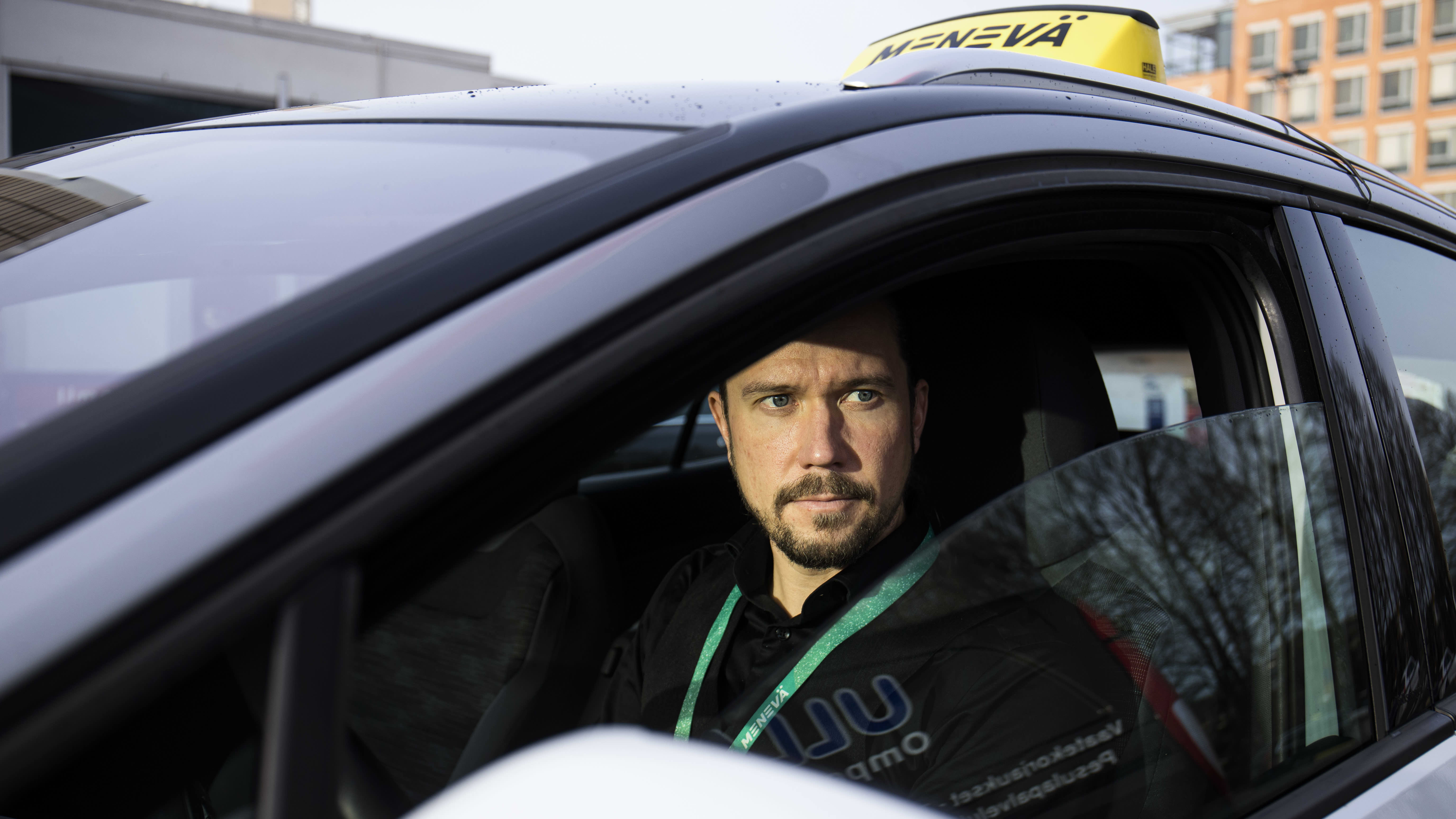 Yrittäjä Jani Viljakainen istuu sähköisessä taksiautossaan.