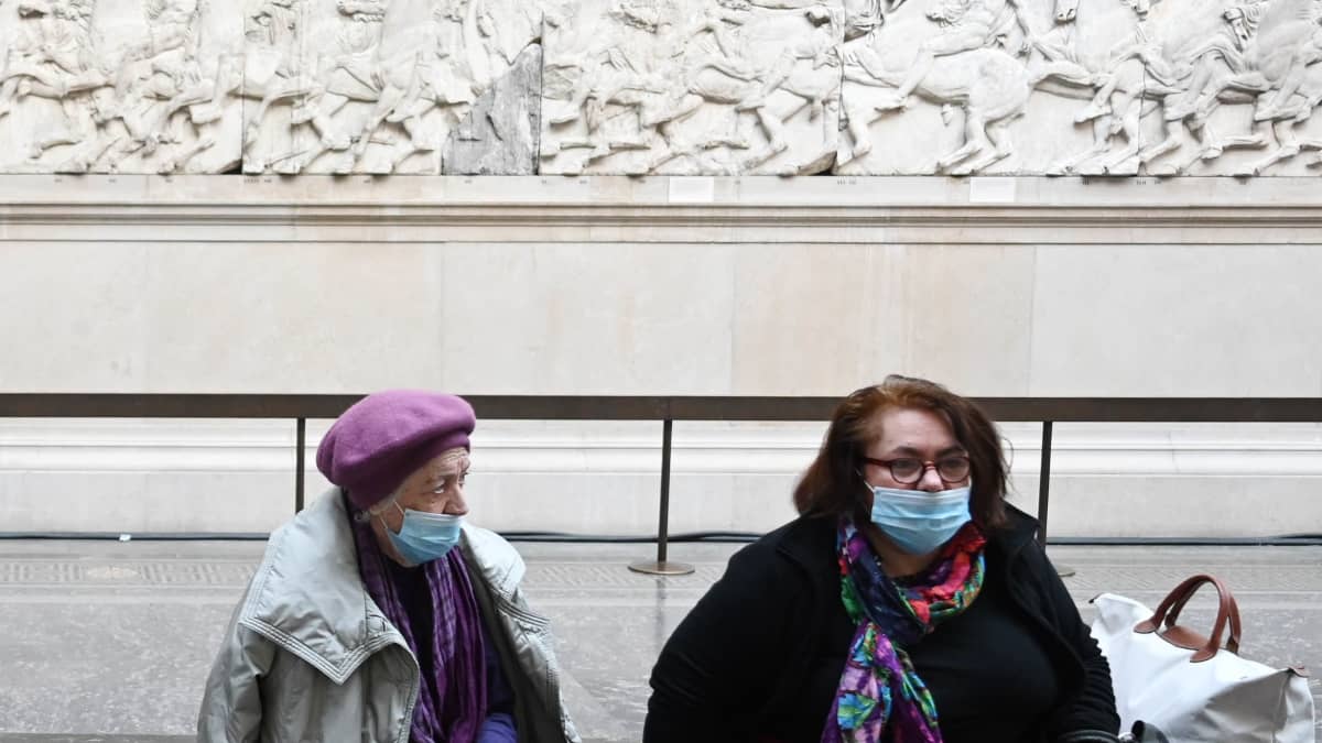 Kaksi naista istui Parthenonin marmoriveistosten edessä British Museumissa. 