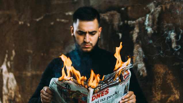 En man läser en brinnande tidning.