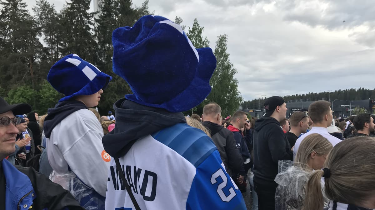 Kaksi poikaa Suomi-paidat ja hatut päässään katsomassa kultajuhlaa.