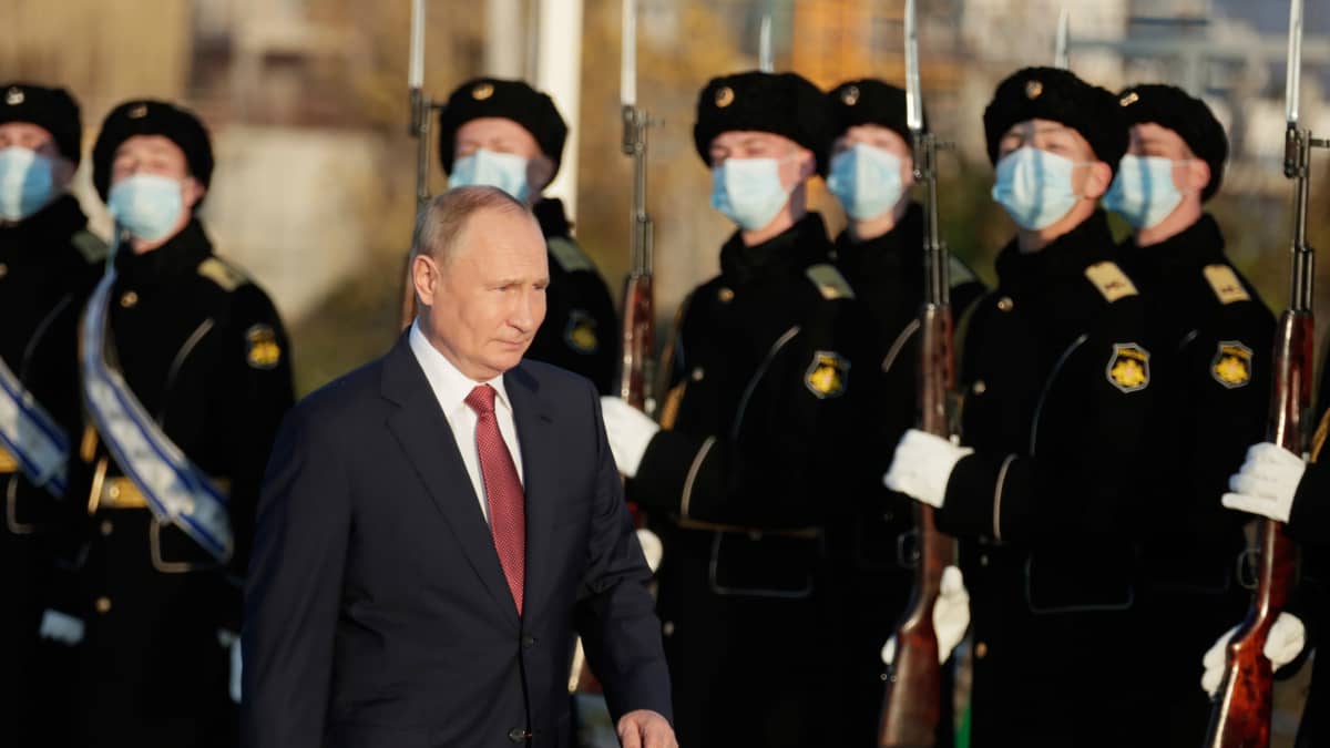 Putin kävelee kunniavartiosotilaiden ohi, sotilailla kasvomaskit. 