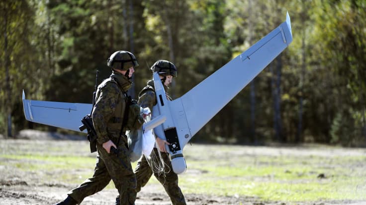 Suomen puolustusvoimien sotilaat kantava droonia. 