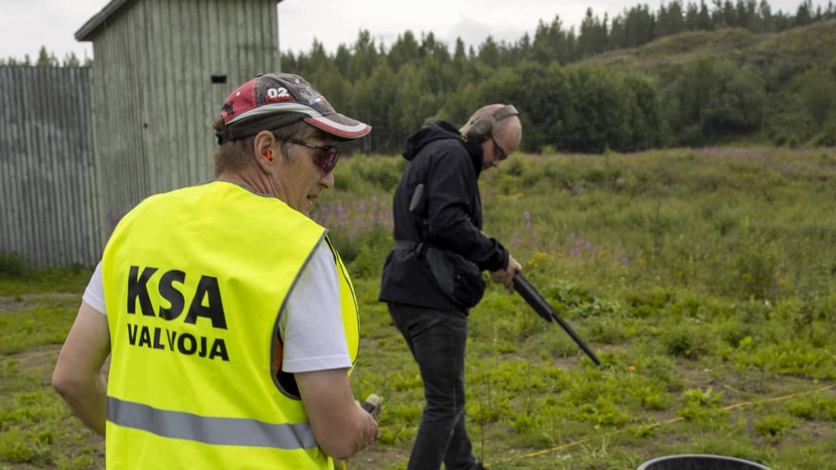 Mies ampumassa haulikolla ampumaseuran valvojan alaisuudessa