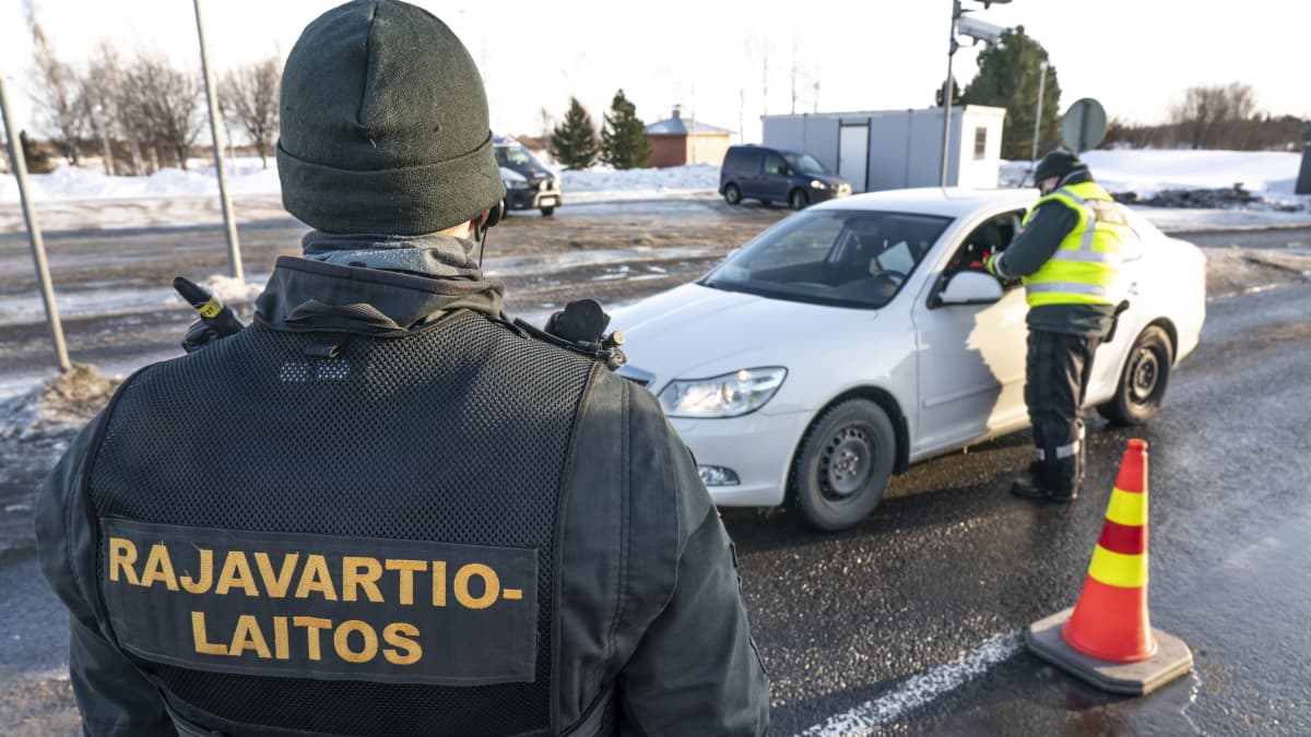 Två gränsbevakare checkar en personbil vid ett gränsövergångsställe.