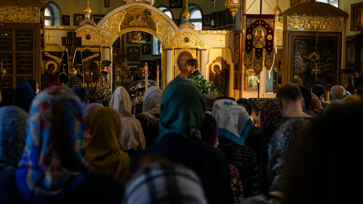 Ortodoksisen kirkon jumalanpalvelus, pappi edessä johtaa toimitusta, ihmiset seisovat pää kumartuneena.