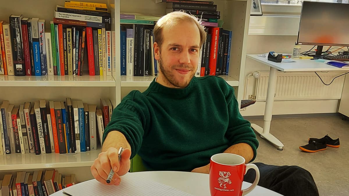 Georg Boldt sitter vid sitt arbetsbord framför en bokhylla.