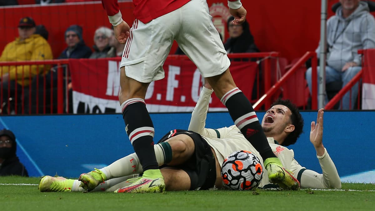 Cristiano Ronaldo potkaisee nurmen pinnassa makaavan Curtis Jonesin kainalossa olevaa palloa. Ronaldo sai tilanteesta varoituksen.