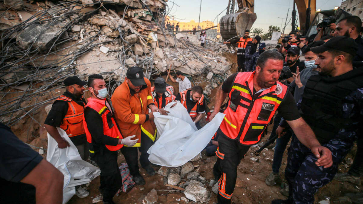 Palestiinalaiset pelastustyöntekijät kantavat pommituksissa kuollutta pois raunioista Gazassa 13.5.2021.