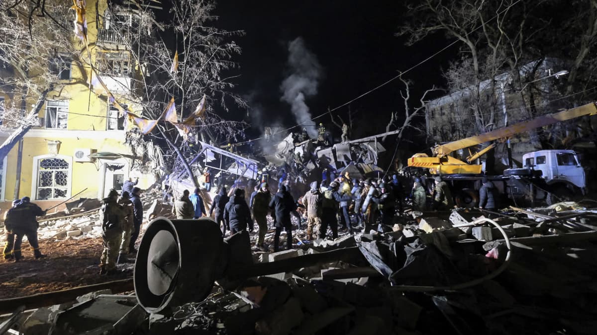 Ukrainalaiset pelastustyöntekijät työskenetelevät pommituksen jäljissä aukiolla asuintalojen keskellä.