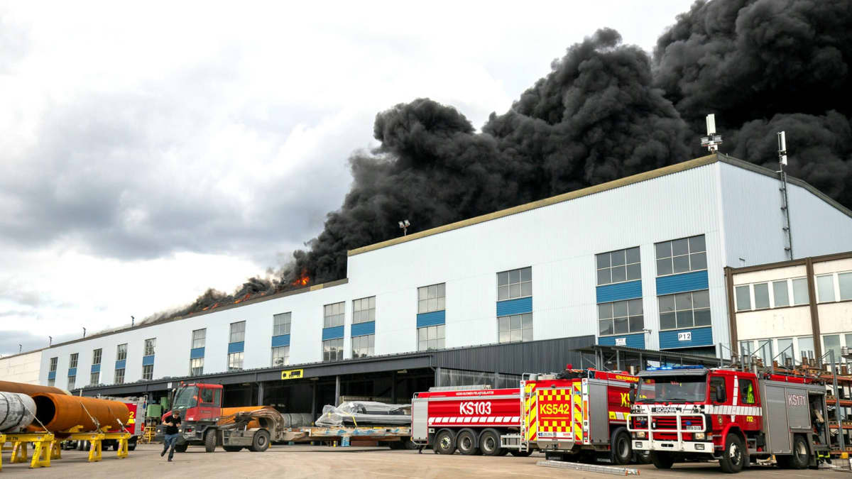 Brandbilar invid brinnande fabriksbyggnad. 
