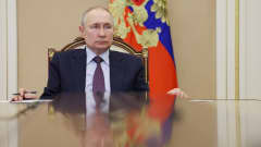 Vladimir Putin istuu pöydän takana.