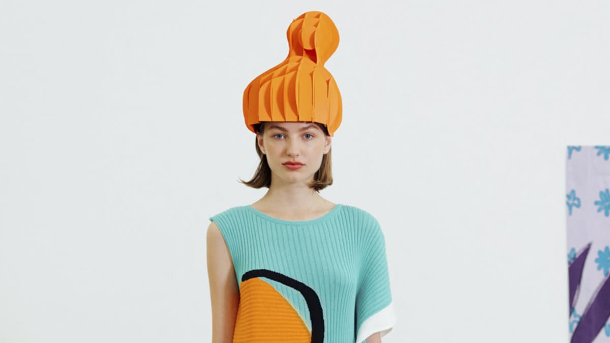 Malli erikoisessa hatussa ja mekossa jossa abstrakti kuvio.