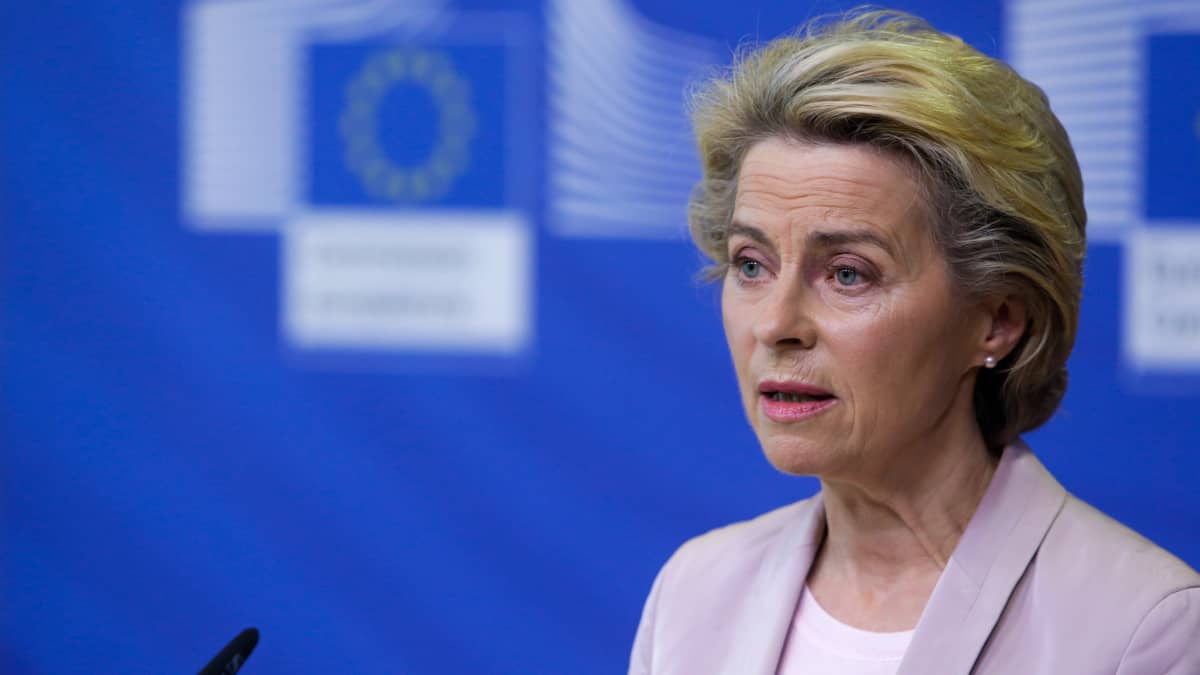 Ursula von der Leyen står och talar i en mikrofon framför en blå vägg med EU-flagga.