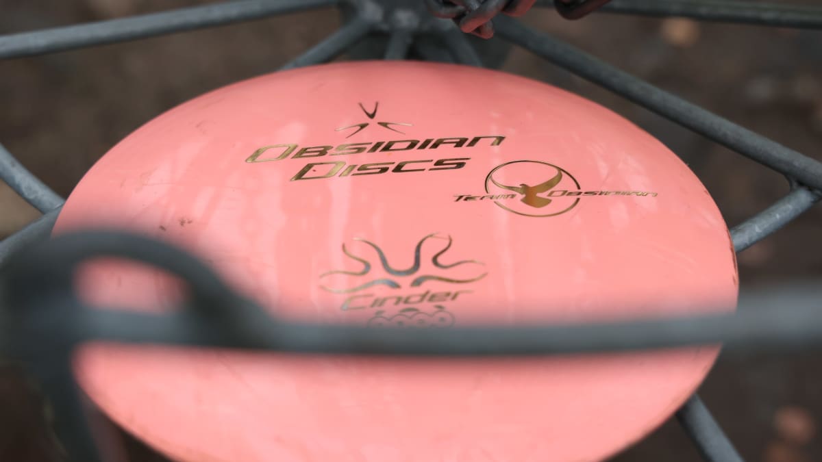 Vaaleanpunainen frisbeegolfkiekko maalikorissa.