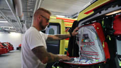 Ensihoitaja tarkastaa lääkelaukkua autotallissa ambulanssin takaosassa.