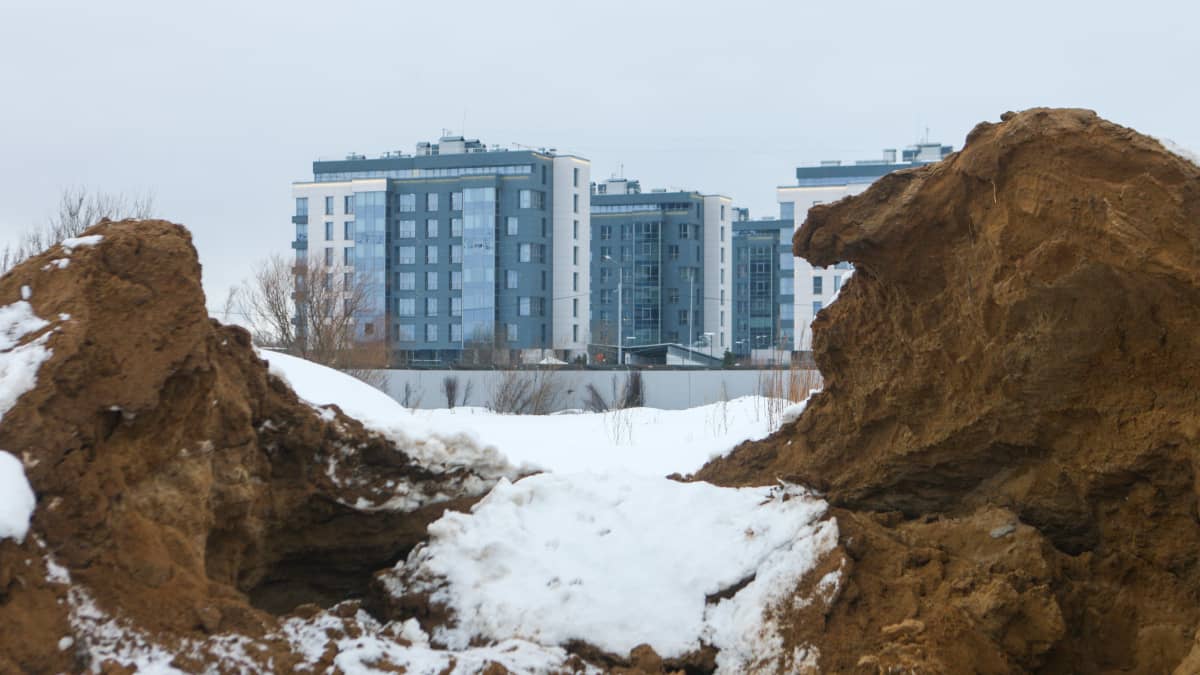 Hiekkakasan takana näkyy uusia kerrostaloja Pietarissa osoitteessa Primorskij Prospekt 78. 