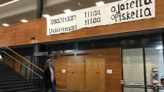 Opiskelija kävelee Tampereen yliopiston Linna-rakennuksen alakerrassa. Seinällä on banderolli, jossa lukee: Vaaditaan tilaa opiskella. 