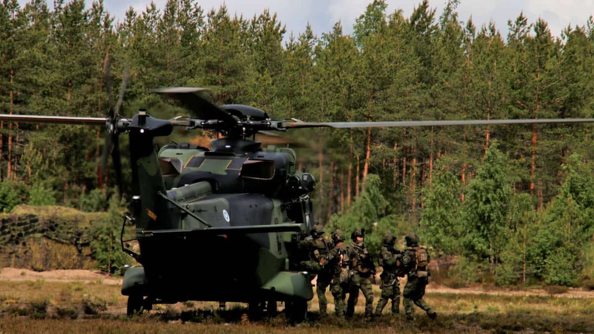 Puolustusvoimien NH-90 kuljetushelikopteri ja Utin jääkärirykmentin erikoisjoukkojen sotilaita kopterin vierellä Utin lentokentällä toimintanäytöksessä Kouvolassa.