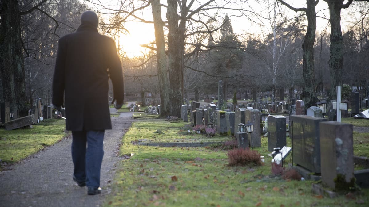 mies kävelee hautausmaalla
