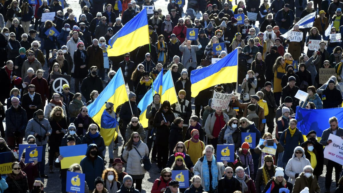 Mielenosoittajat pitelevät Ukrainan lippuja ja kylttejä Senaatintorilla.