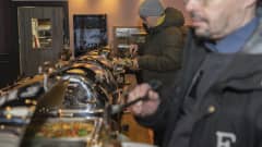 Ruokaa laitetaan lautaselle seisovasta pöydästä.