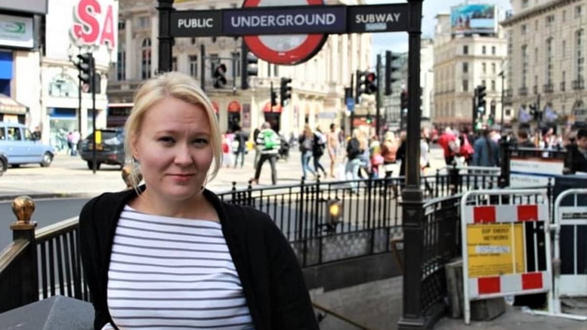 Mari Markkanen nojaa kaiteeseen Lontoossa. taustalla vilkas katu ja kyltti Underground. 