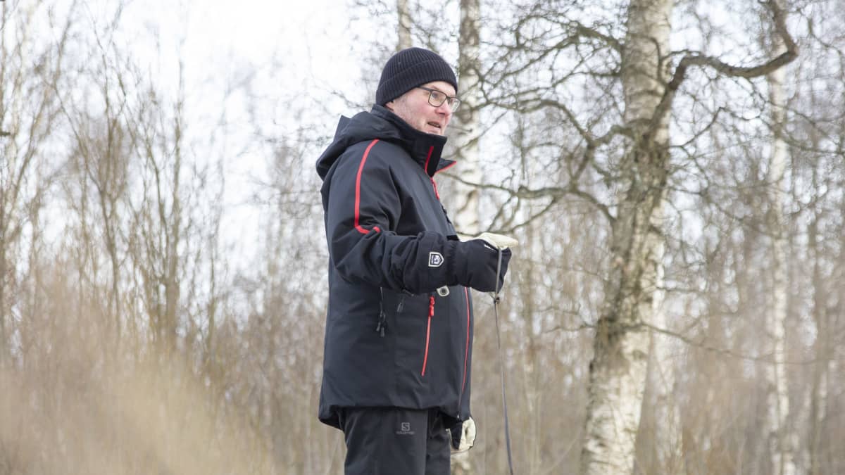 Jouko Haapalainen kävelee lumisella tiellä ja kävelyttää mustaa snautseria.