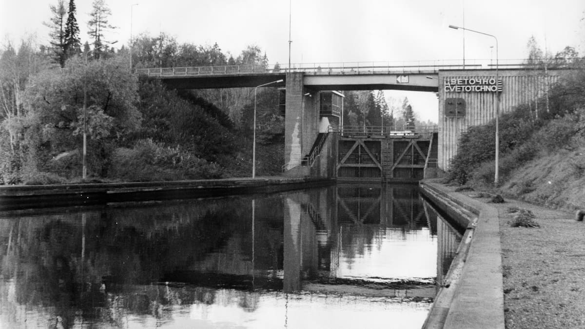 Mustavalkoinen kuva, jossa keskellä kapea kanava je sen yli menee silta. 