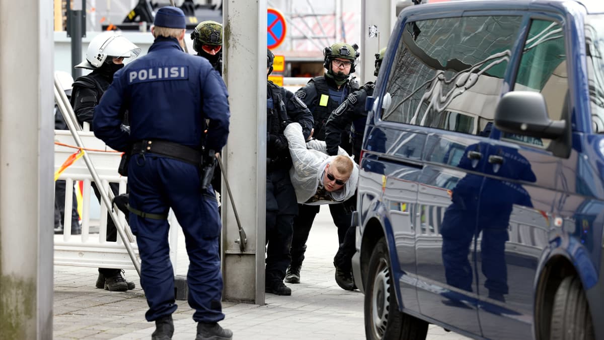 Poliisi pidättää mielenosoittajan.